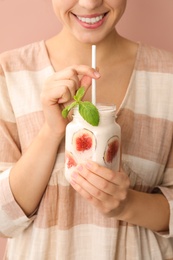 Photo of Woman holding mason jar with fig smoothie on pink background, closeup