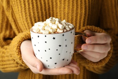 Photo of Woman holding cup of aromatic cocoa with marshmallows, closeup