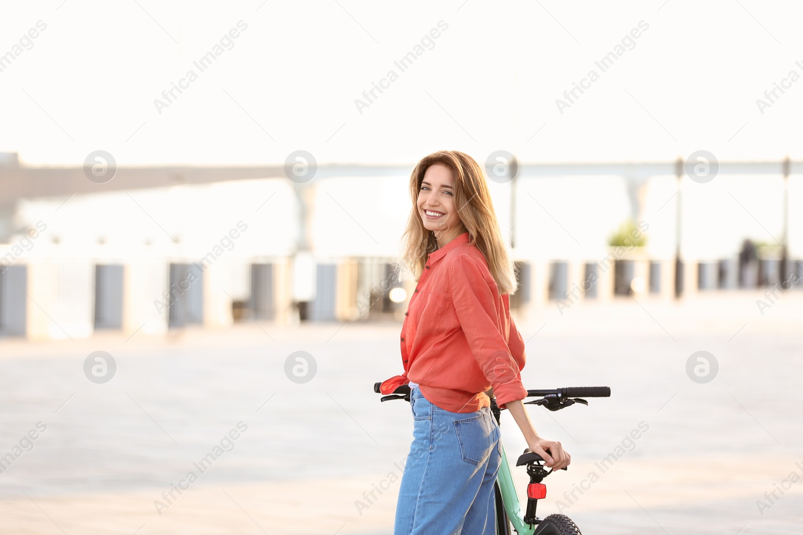 Photo of Young woman with bicycle in city on sunny day