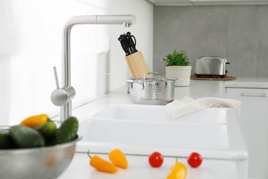 Photo of Fresh clean vegetables on kitchen counter near sink