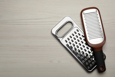 Photo of Modern graters on white wooden table, flat lay. Space for text