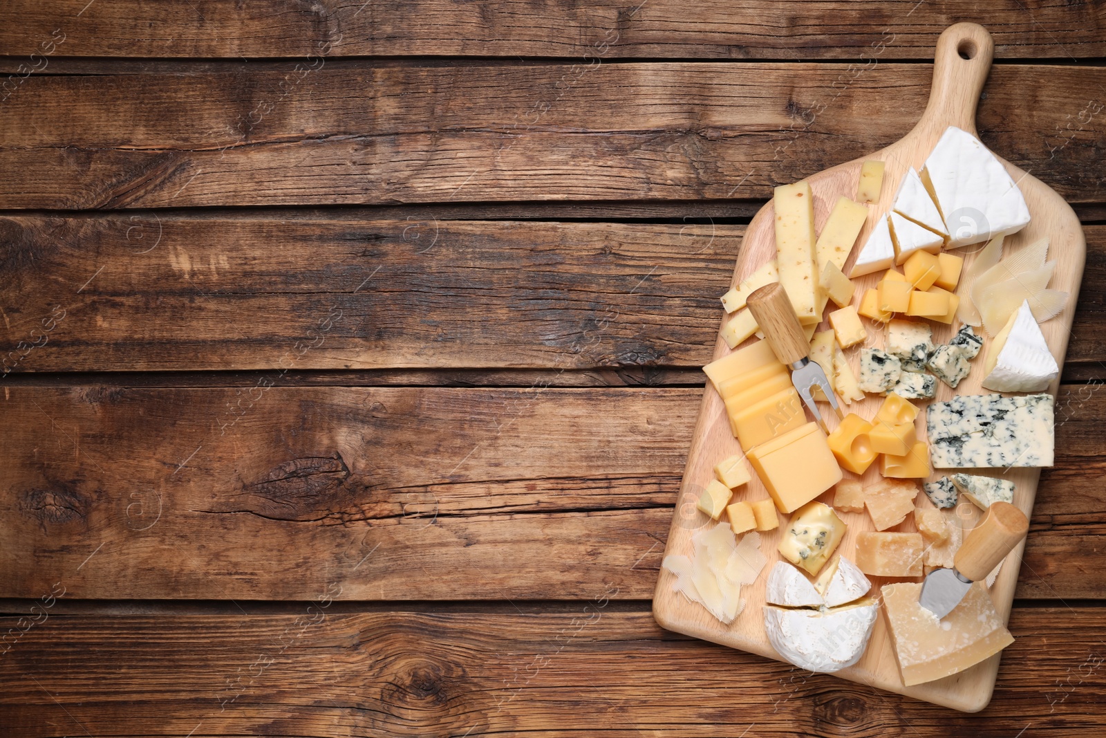 Photo of Cheese plate on wooden table, top view. Space for text