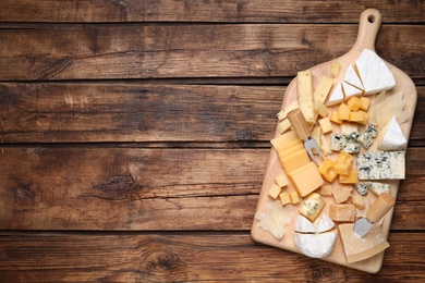 Photo of Cheese plate on wooden table, top view. Space for text