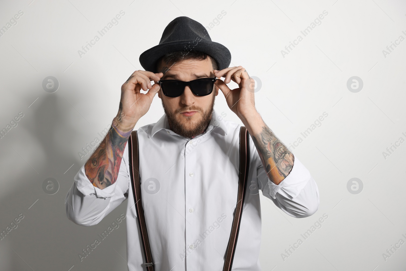 Photo of Handsome hipster man wearing stylish sunglasses on light grey background