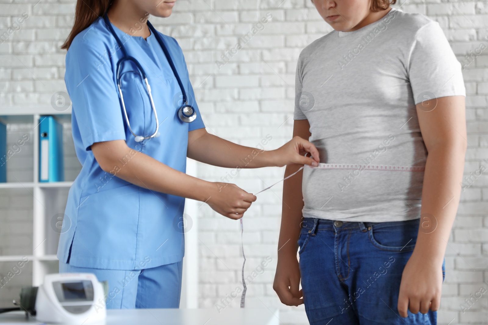 Photo of Female doctor measuring overweight boy in clinic, closeup view