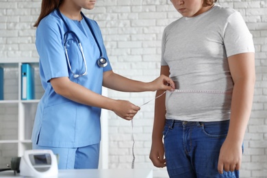 Photo of Female doctor measuring overweight boy in clinic, closeup view
