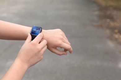Image of Woman using smart watch to check time or heart rate outdoors, closeup
