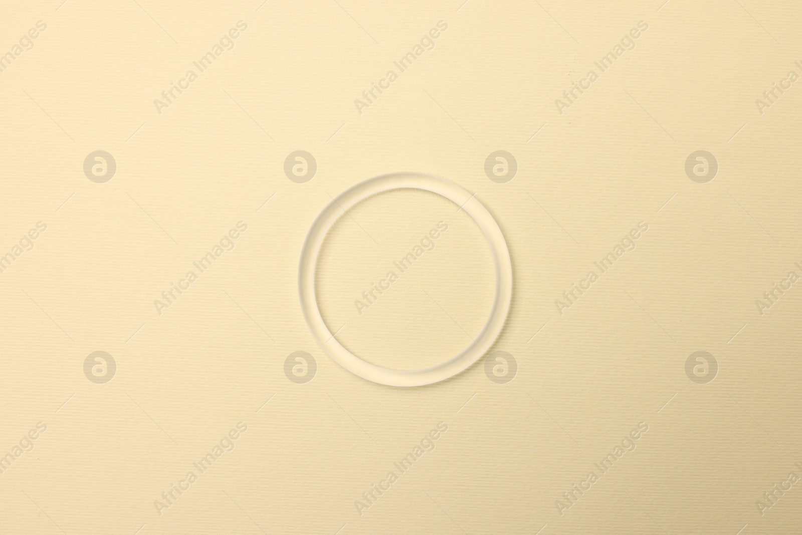 Photo of Diaphragm vaginal contraceptive ring on light yellow background, top view