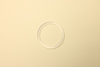 Diaphragm vaginal contraceptive ring on light yellow background, top view