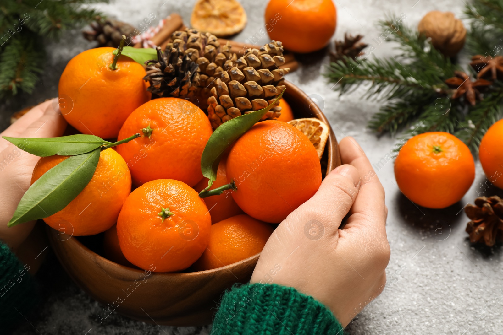 Photo of Woman with fresh tangerines at table, closeup. Christmas atmosphere