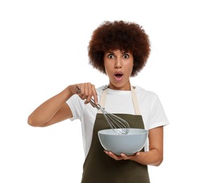Emotional young woman in apron holding bowl and whisk on white background
