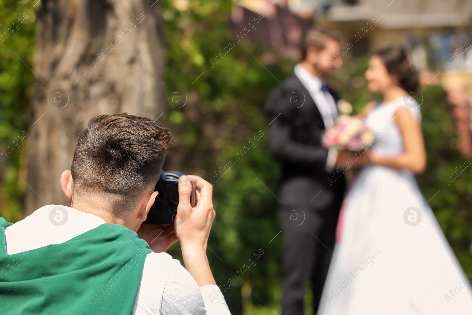 Photo of Professional photographer taking photo of wedding couple, outdoors