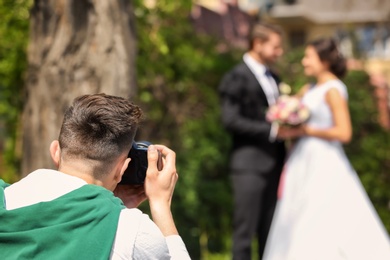 Professional photographer taking photo of wedding couple, outdoors