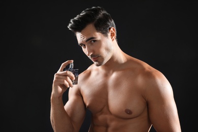 Photo of Handsome young man using perfume on black background
