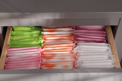 Open cabinet drawer with different menstrual pads, closeup