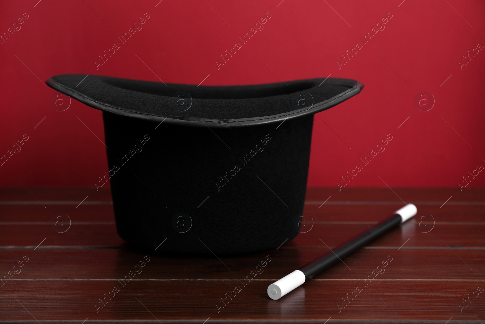 Photo of Black top hat and wand on wooden table. Magician equipment