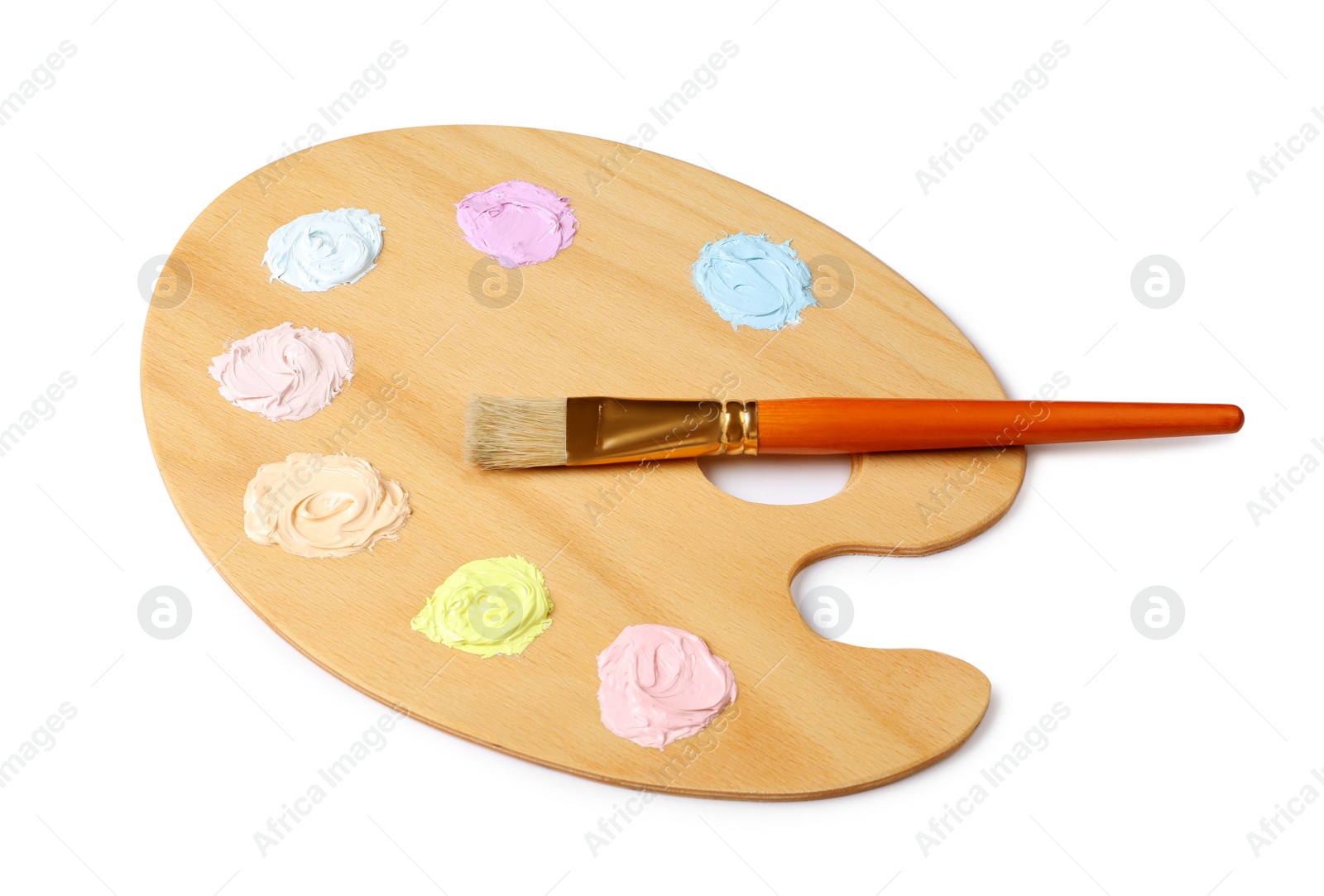 Photo of Wooden artist's palette with samples of pastel paints and brush isolated on white