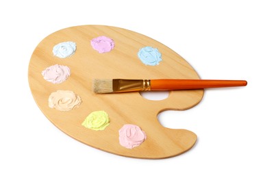 Photo of Wooden artist's palette with samples of pastel paints and brush isolated on white