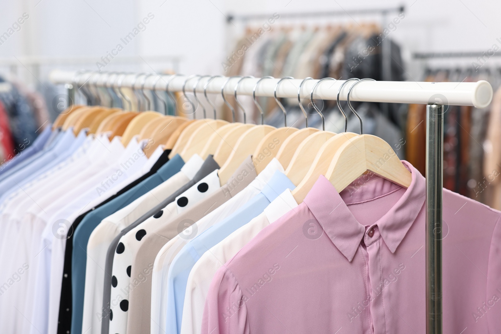 Photo of Dry-cleaning service. Many different clothes hanging on rack indoors, closeup