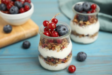 Delicious yogurt parfait with fresh berries on turquoise wooden table, closeup