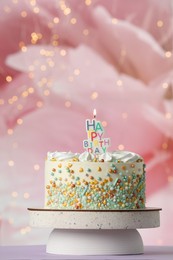 Photo of Beautiful birthday cake with burning candle on violet table