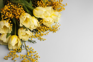 Bouquet with beautiful tulips and mimosa flowers on light grey background, space for text