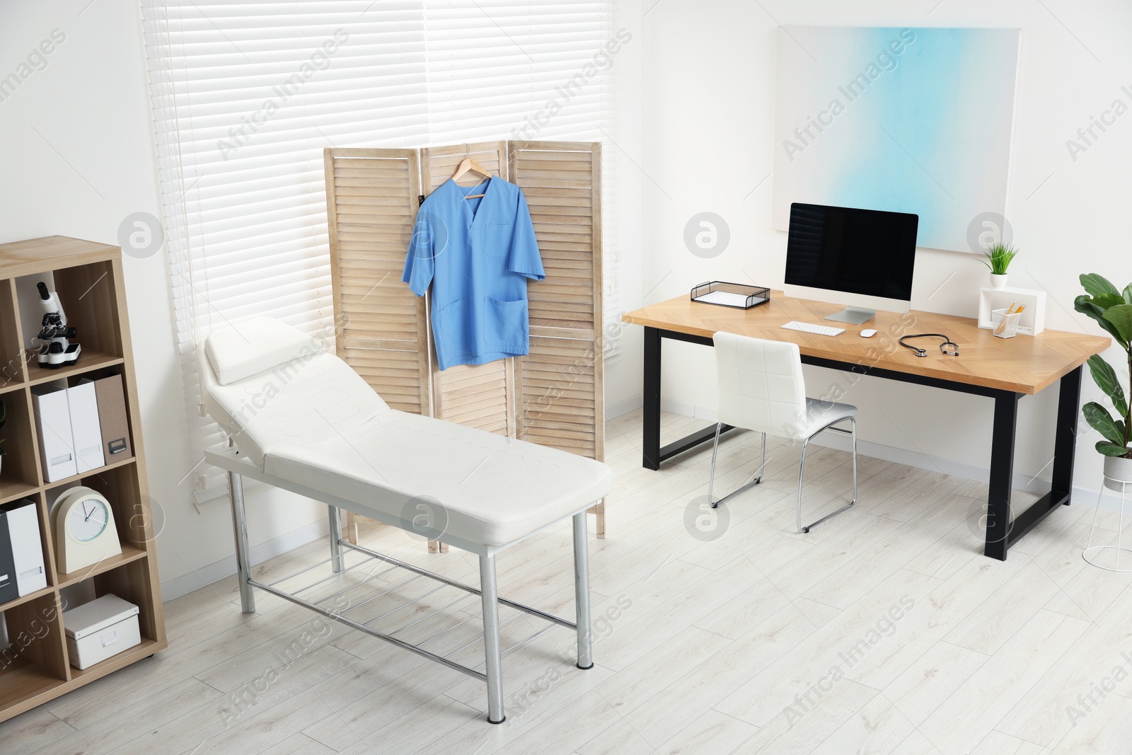 Photo of Modern medical office with doctor's workplace and examination table in clinic