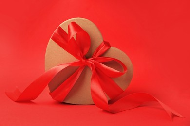 Photo of Beautiful heart shaped gift box with bow on red background