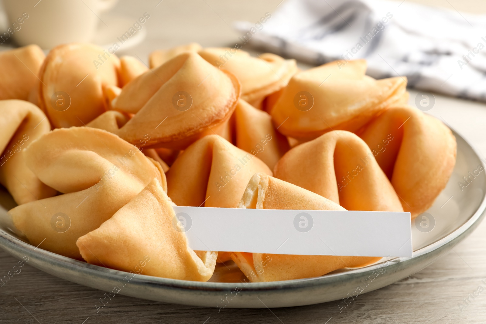 Photo of Tasty fortune cookies and paper with prediction on wooden table, closeup. Space for text