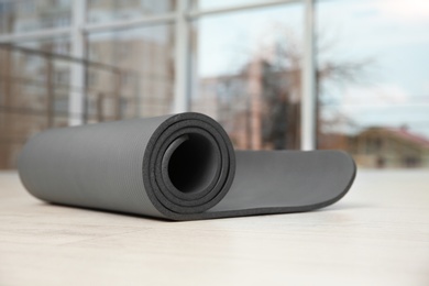 Photo of Rolled grey yoga mat on floor indoors