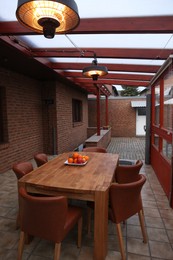 Photo of Wooden table with fruits and stylish chairs on terrace