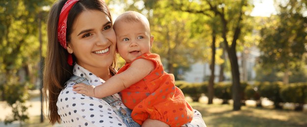 Happy mother with adorable baby in park on sunny day, space for text. Banner design 