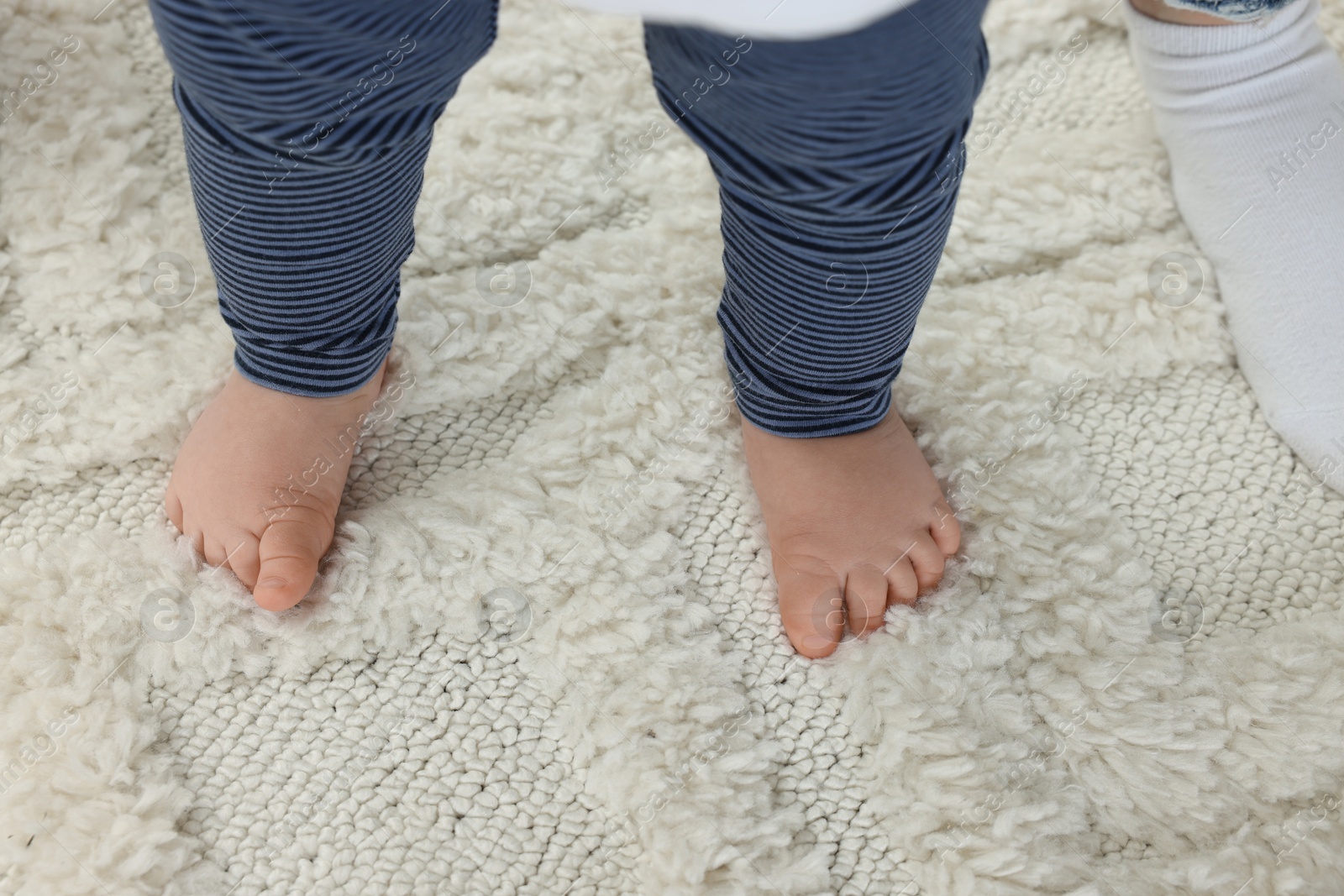 Photo of Mother and baby standing on soft carpet, closeup