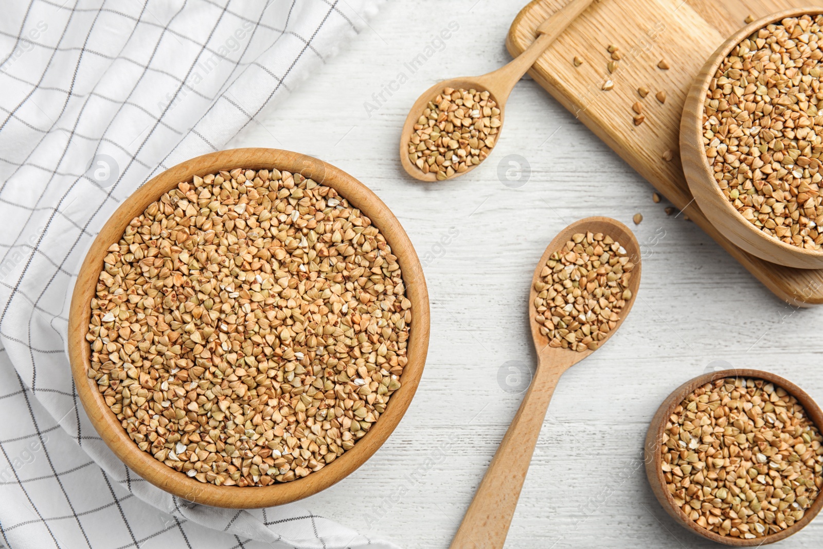 Photo of Uncooked green buckwheat grains on white wooden table, flat lay