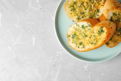 Photo of Slices of toasted bread with garlic, cheese and herbs on grey table, top view. Space for text