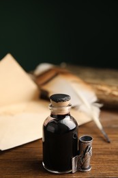 Feather pen, bottle of ink and old paper on wooden table