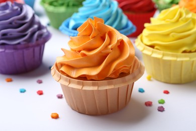 Photo of Many tasty cupcakes with bright cream and sprinkles on white background, closeup