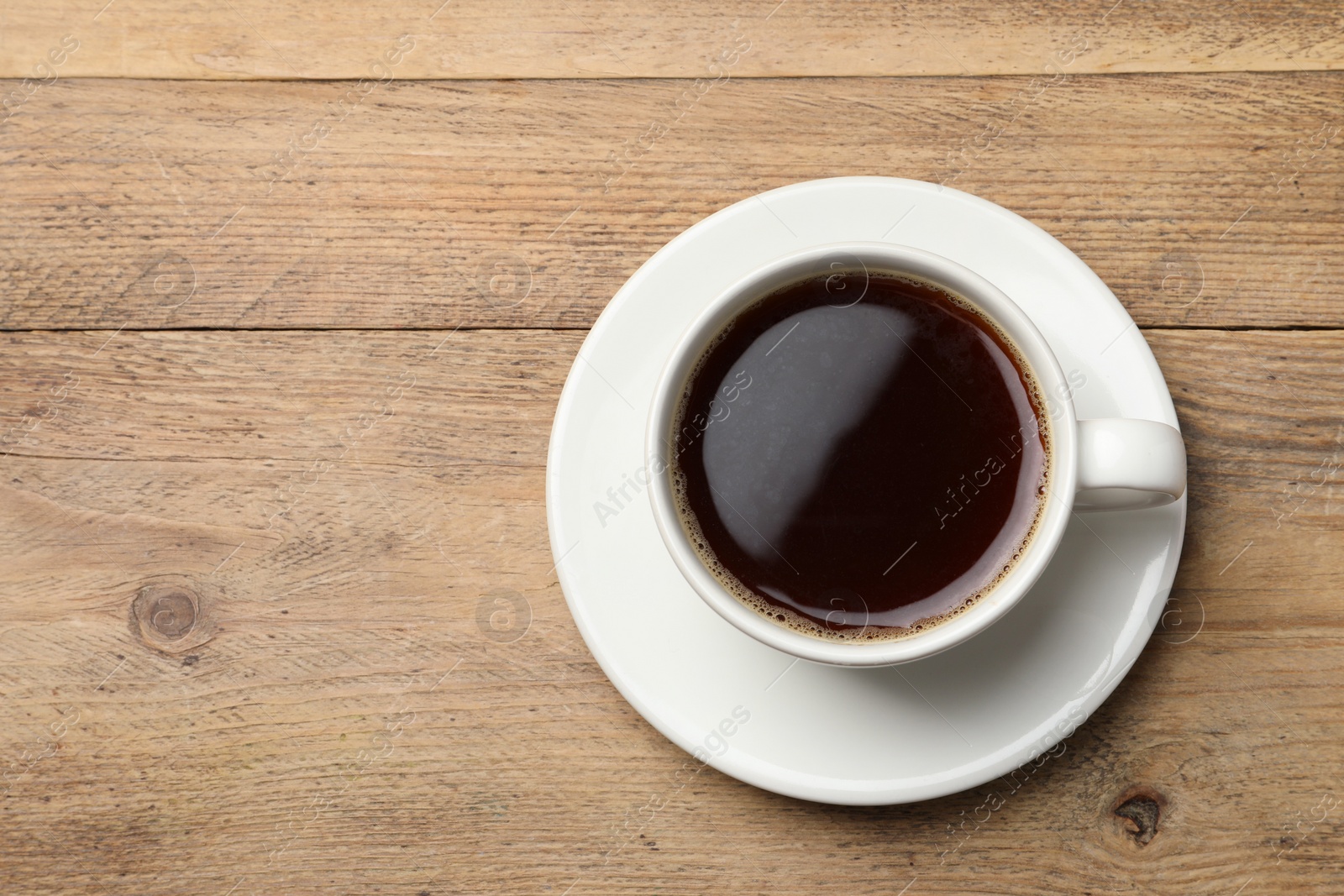 Photo of Cup of aromatic coffee on wooden table, top view. Space for text