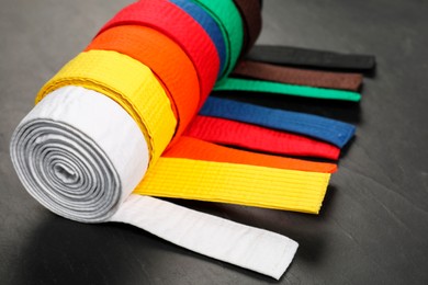 Photo of Colorful karate belts on gray background, closeup