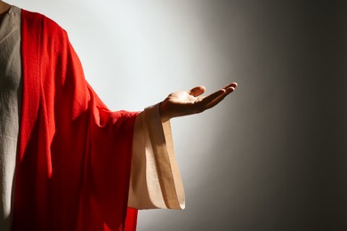 Photo of Jesus Christ reaching out his hand on grey background, closeup view