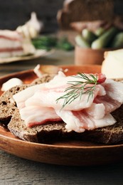 Tasty salt pork with rye bread and dill on wooden table, closeup