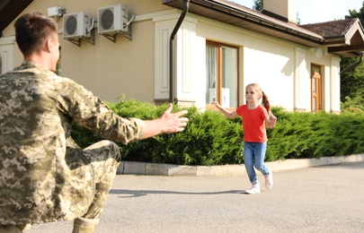 Photo of Father in military uniform and little daughter running to him outdoors