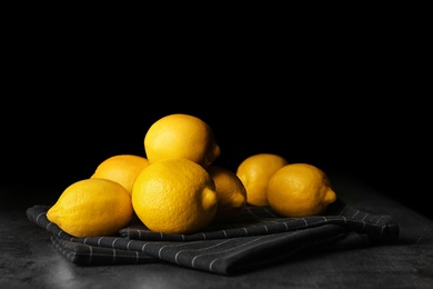 Photo of Ripe whole lemons on table against dark background