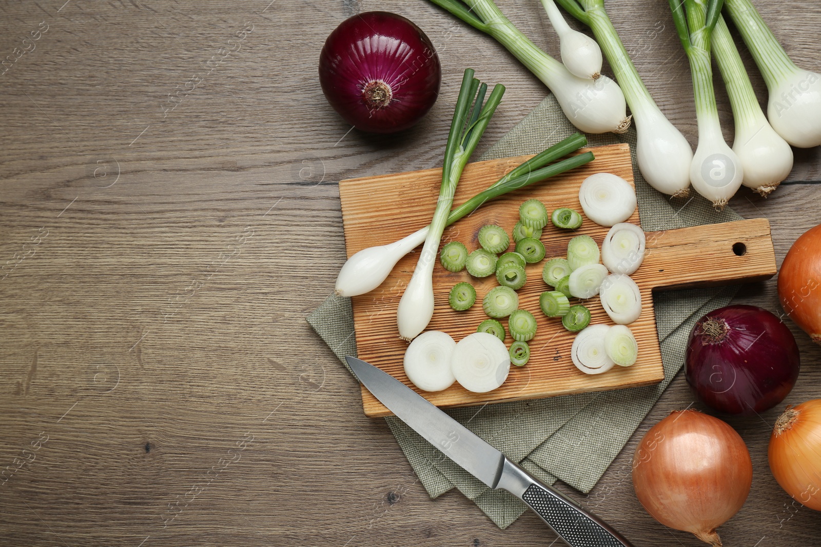 Photo of Different kinds of onions on wooden table, flat lay. Space for text