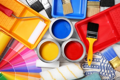 Flat lay composition with cans of paint and decorator tools on wooden background