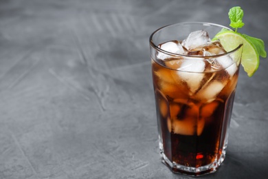 Photo of Glass of Rum and Cola cocktail on grey stone table, space for text