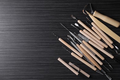 Photo of Clay and set of modeling tools on dark gray wooden table, flat lay. Space for text