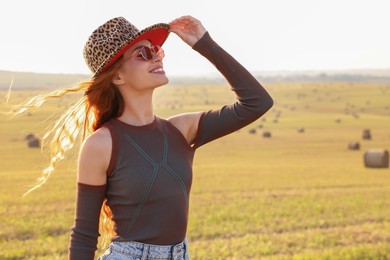 Photo of Beautiful happy hippie woman in hat in field, space for text