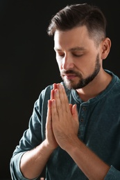 Photo of Man with hands clasped together for prayer on black background