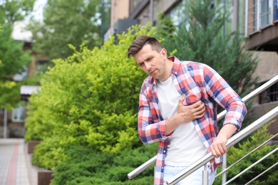 Photo of Young man having chest pain outdoors. Heart attack